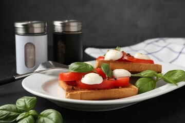 Tasty sandwiches with mozzarella cheese, tomatoes and basil on dark table against grey background,...