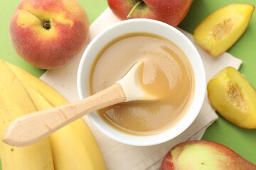 Baby food. Tasty puree in bowl and ingredients on green background, flat lay