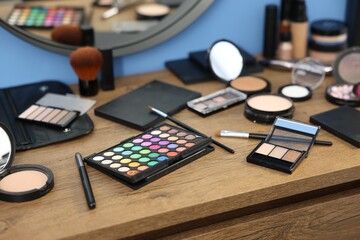 Different makeup products on wooden table indoors, closeup