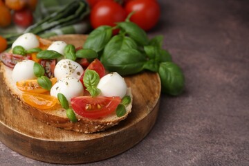 Tasty sandwich with mozzarella cheese, tomatoes and basil on brown table, closeup