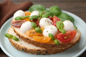 Tasty sandwich with mozzarella cheese, tomatoes and basil on wooden table, closeup