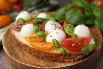 Tasty sandwich with mozzarella cheese, tomatoes and basil on brown table, closeup