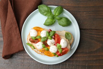 Tasty sandwich with mozzarella cheese, tomatoes and basil on wooden table, top view