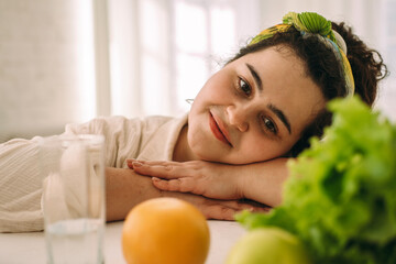 Portrait of a young positive curly-haired plus-size woman with fruits and salad. Healthy eating and healthy lifestyle.