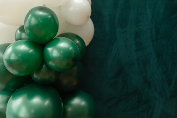 Elegant green and dark green balloons on a textured dark emerald green background. Perfect for celebrations, parties, or design backdrops with a luxurious feel.