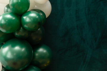 Elegant green and dark green balloons on a textured dark emerald green background. Perfect for celebrations, parties, or design backdrops with a luxurious feel.