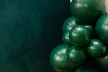 Elegant green and dark green balloons on a textured dark emerald green background. Perfect for celebrations, parties, or design backdrops with a luxurious feel.