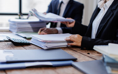 Two busy business professionals man and woman business leaders partners checking document reading financial report talking working together on laptop computer in office at corporate meeting.
