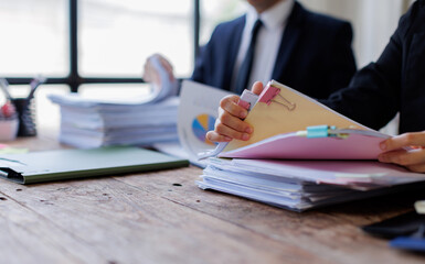 Two busy business professionals man and woman business leaders partners checking document reading financial report talking working together on laptop computer in office at corporate meeting.
