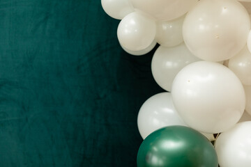 Elegant green and dark green balloons on a textured dark emerald green background. Perfect for celebrations, parties, or design backdrops with a luxurious feel.