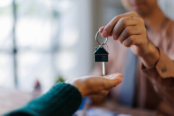 Real estate agent giving house key to the client after signing making sign insurance form agreement, the real estate contract. Home and real estate trading concept.
