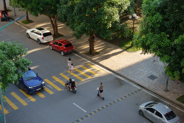Busy street crossing in Hanoi, Vietnam showcasing everyday life during a sunny afternoon