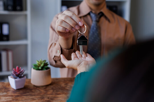 Real estate agent giving house key to the client after signing making sign insurance form agreement, the real estate contract. Home and real estate trading concept.
