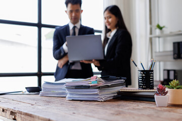 Photo of young Asian business people working and standing near the window in workplace	
