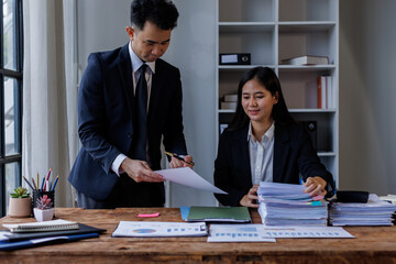 Photo of young Asian business people working and standing near the window in workplace	
