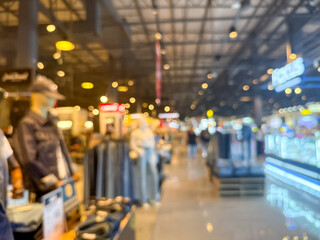 blurry image showing the interior of a shopping mall. The scene is out of focus, with indistinct shops, lights, and people walking.