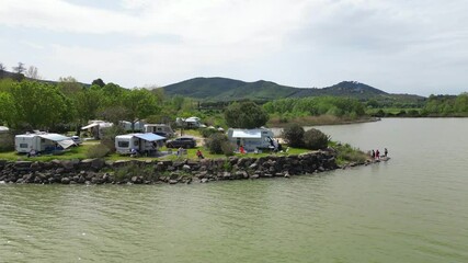 Europe, Italy, Umbria, 06,08,2025 drone  view of naturist camping with camper tents on the lakeside in Pontile Sant'arcangelo  Trasimeno lake , summer destination attraction 