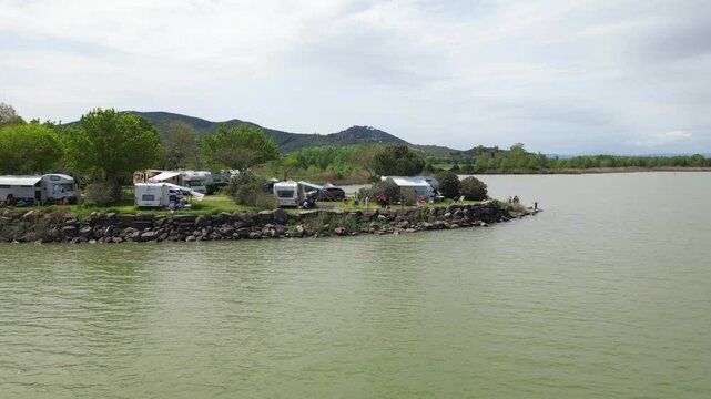 Europe, Italy, Umbria, 06,08,2025 drone  view of naturist camping with camper tents on the lakeside in Pontile Sant'arcangelo  Trasimeno lake , summer destination attraction 