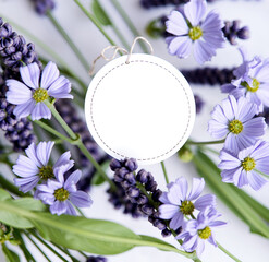 Beautiful lavender and blue tiny flowers with price tag. Floral motif of fresh flowers with round blank paper white label, frame for text. Background.