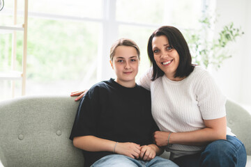 mother with teen girl, having great time on sofa