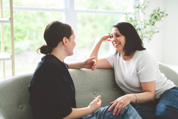 mother with teen girl, having great time speaking on sofa