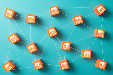 Orange wooden blocks with storefront icons connected in a network. Concept for business franchise, chain stores, retail expansion, distribution network,business network, supply chain management.