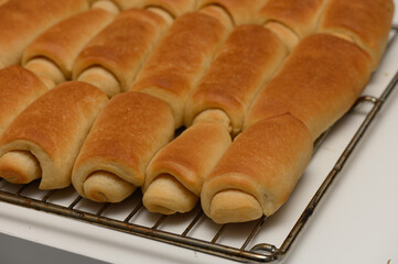 Golden Parker House rolls resting on a wire rack, just out of the oven.