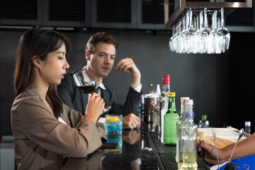 Female office worker drinking cocktail in rooftop bar after work with male coworker at rooftop bar