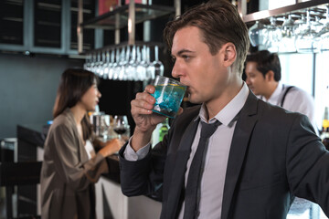 Handsome office man drinking cocktail in rooftop bar after work with female coworker