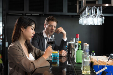 Handsome office man drinking cocktail in rooftop bar after work with female coworker