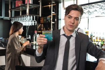 Handsome office man drinking cocktail in rooftop bar after work with female coworker