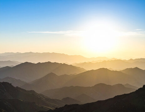 Silhouetted mountains at sunrise under a clear blue sky