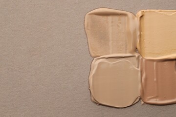 Colorful skin foundations on grey background, flat lay. Space for text