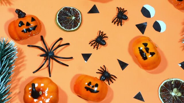 Halloween frame with party decorations of pumpkins, bats, ghosts, spiders on orange background from above. Happy halloween card in flat lay style.