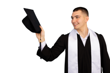 Young man wearing graduation gown holding his mortarboard and smiling, isolated on transparent background