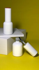 Nail polish, white nail polish bottle with brush on yellow background, manicure concept