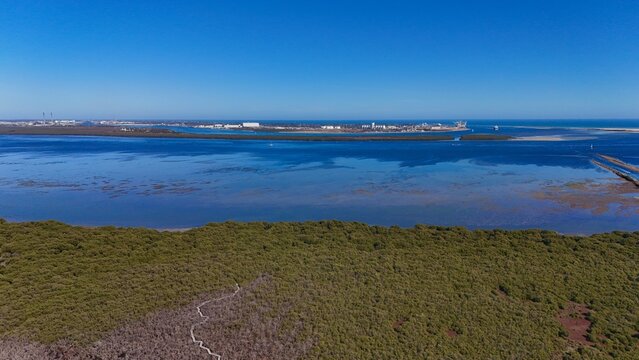 Stunning aerial view of the St Kilda Mangrove Trail and surrounding salt pans in North Adelaide, South Australia, showcasing unique wetland ecosystems, tidal flats, and distant hills under clear blue