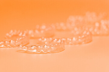 Orthodontic silicone aligner background. Advertisement of invisible braces retainer. Medical website concept. Pros and cons of aligners. peach saturated background