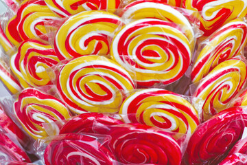 Vibrant red and yellow swirl lollipops on street shop display