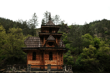Fototapeta premium Front view of the Saint Andrew chapel surrounded by forest and cross in the distance in Mokra Gora, Serbia.
