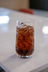 A glass of Cola on the table with bokeh background