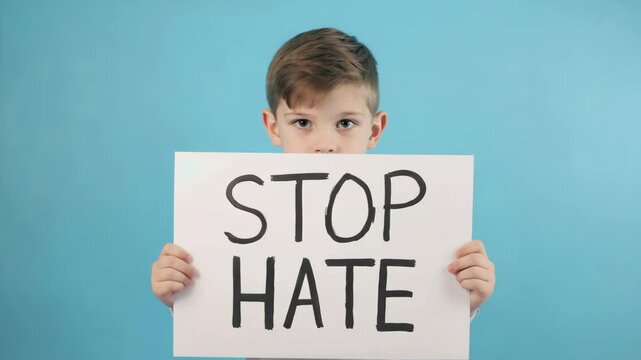 Boy holding stop hate text sign against blue background, promoting justice and peace, anti-racism, equality awareness, education, social justice