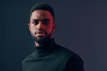 Confident young African man wearing a black turtleneck sweater, showcasing a serious expression...