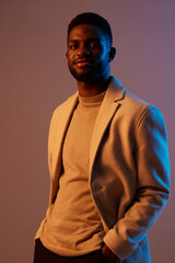 Confident young Black man in modern attire, showcasing styles under vibrant lighting in an artistic portrait Emphasizing elegance and contemporary fashion