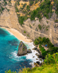 Experience the unparalleled beauty of Diamond Beach on Nusa Penida, Bali. This aerial perspective highlights the stunning contrast of turquoise water, pristine sand, and towering cliffs