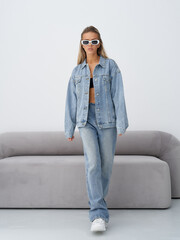 Blonde model showcases stylish denim outfit in modern studio setting
