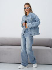 Stylish blonde model poses in trendy denim outfit inside a modern studio