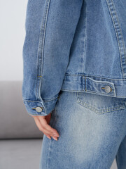Stylish blonde woman modeling casual denim wear in a bright indoor studio setting