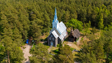 Historic church amidst lush forest on Ruhnu Island, Estonia, showcasing unique architecture