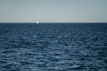 Sailboat gliding smoothly across calm ocean waters under a clear sky
